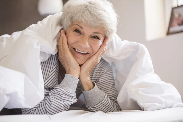 Зрелая женщина улыбается в постели — стоковое фото