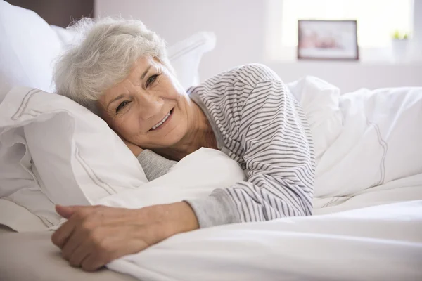 Mogen kvinna ler i sängen — Stockfoto