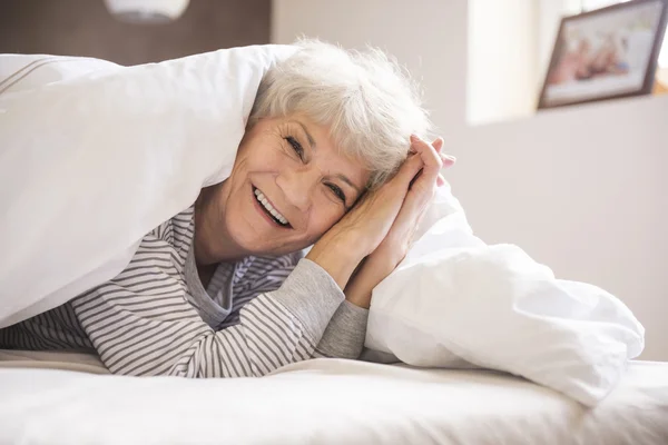 Olgun kadın yatakta gülümseyen — Stok fotoğraf