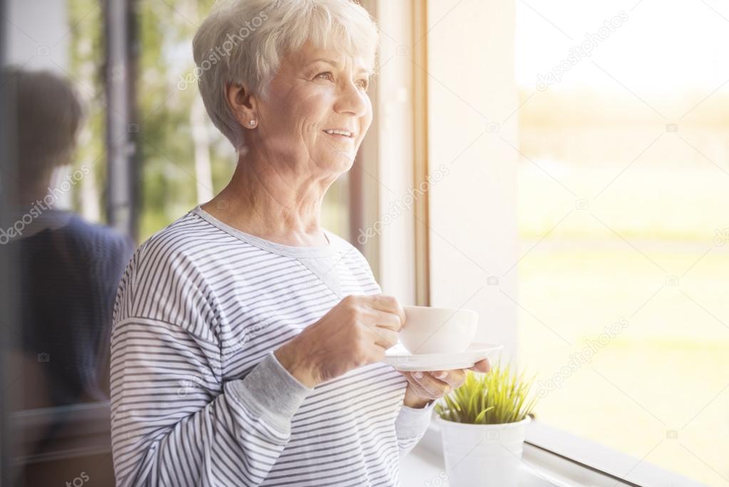 mature woman with coffee near window