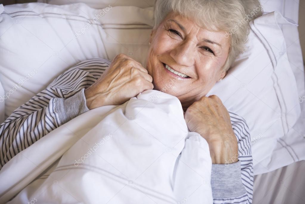 mature woman in bed smiling