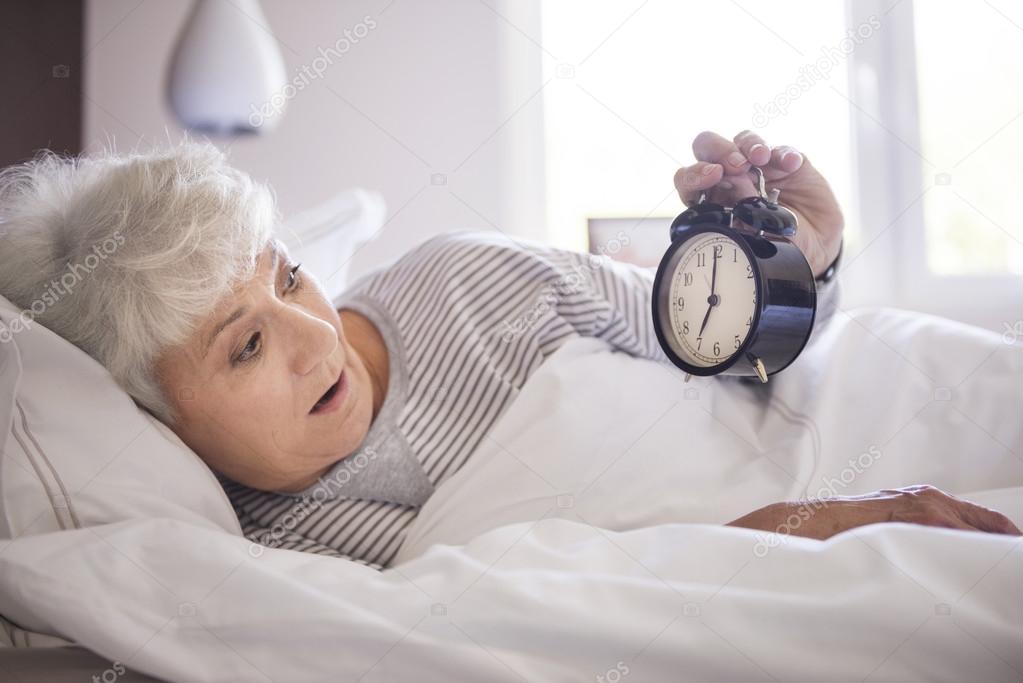 mature woman in bed with clock