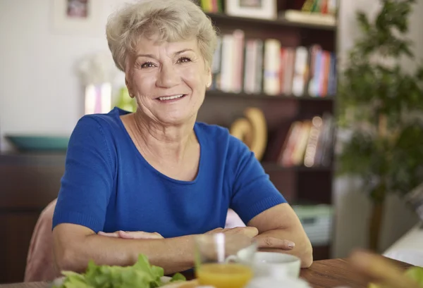 Senior vrouw zitten aan de tafel — Stockfoto