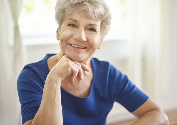 Smiling grandmother sitting at the table — Stock Photo, Image