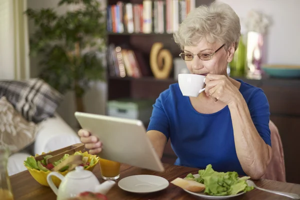 Cheerful senior woman eating breakfast — Stock Photo, Image