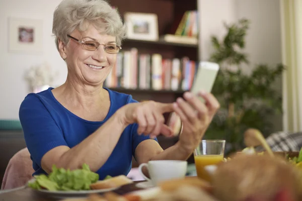 Senior woman make a call during a breakfast — Stock Photo, Image