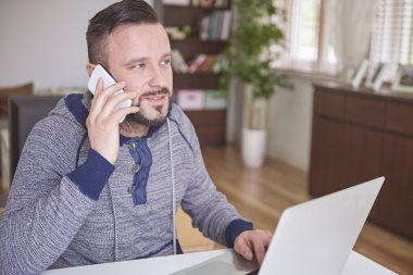 Dizüstü bilgisayar ve cep telefonu adam çalışır