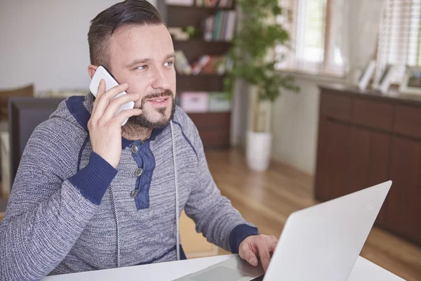 L'uomo lavora su laptop e telefono cellulare — Foto Stock