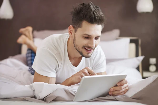 Man using digital tablet in bed — Stock Photo, Image