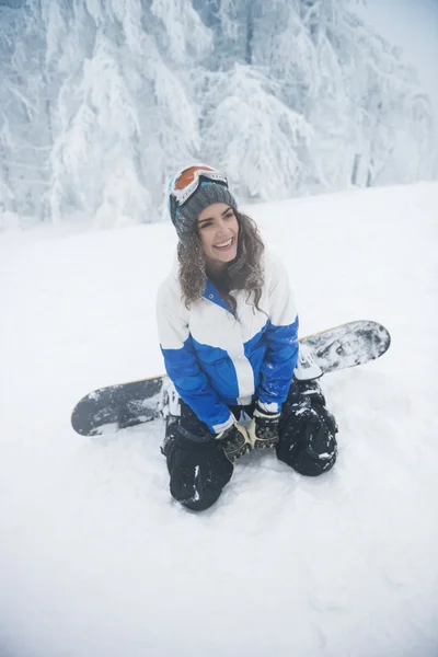 Mujer feliz sentada en la nieve — Foto de Stock