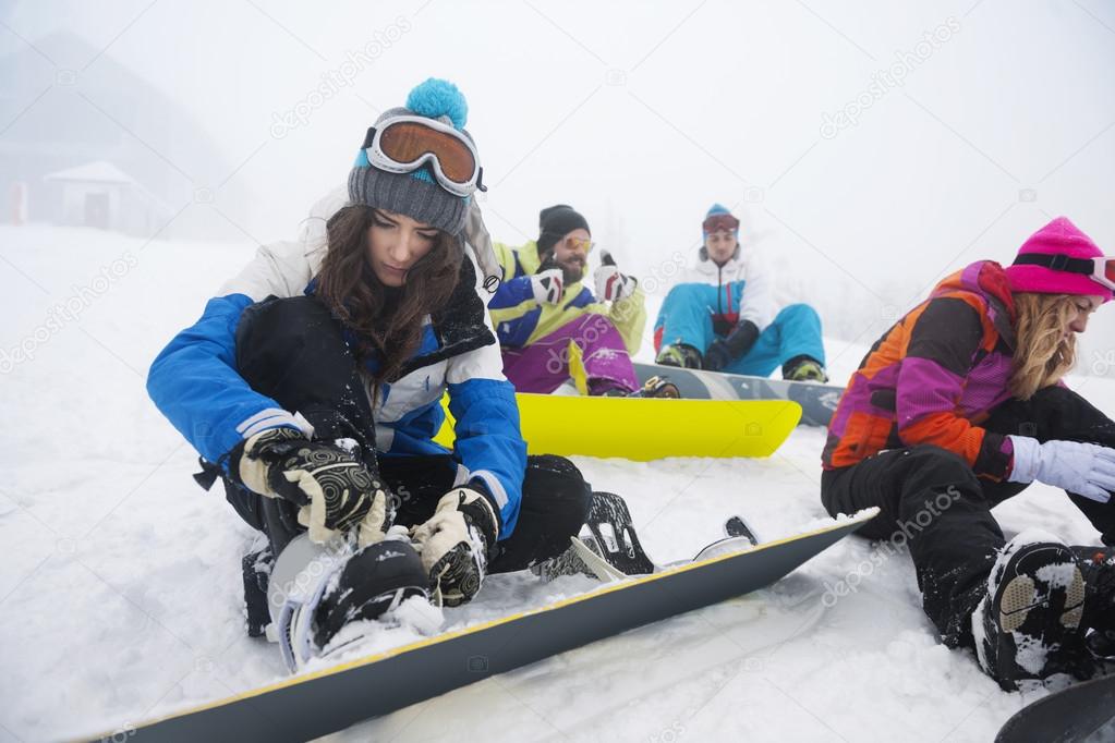 Friends preparing for snowboarding at ski slope