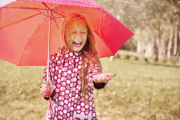 Улыбающаяся девушка с красным зонтиком — стоковое фото
