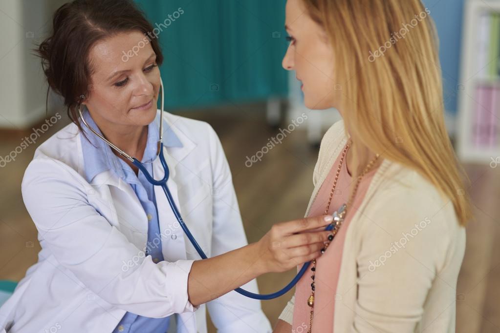 Врач слушает пациента. Девочка на приеме у кардиолога. Девушка на приеме у кардиолога. Прослушивание сердца стетоскопом. Аускультация при гипертонической болезни.