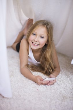 Battaniyenin altında cep telefonu kullanan kız