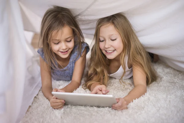 Meisjes met behulp van digitale tablet onder blad. — Stockfoto