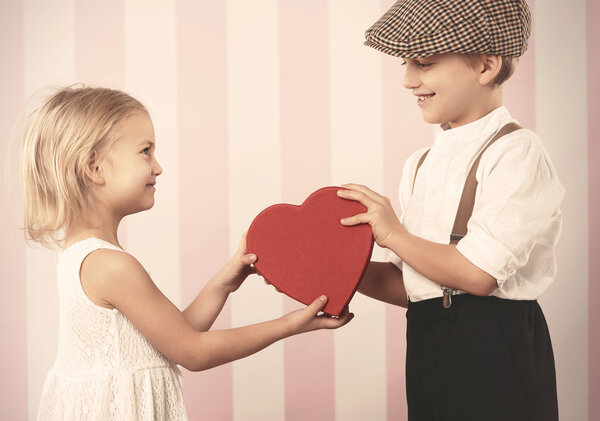 Little couple with red heart in hands