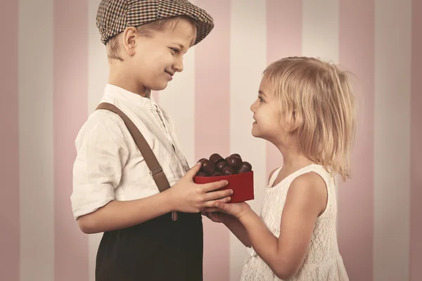 Garoto dando uma caixa de menina de chocolates — Fotografia de Stock