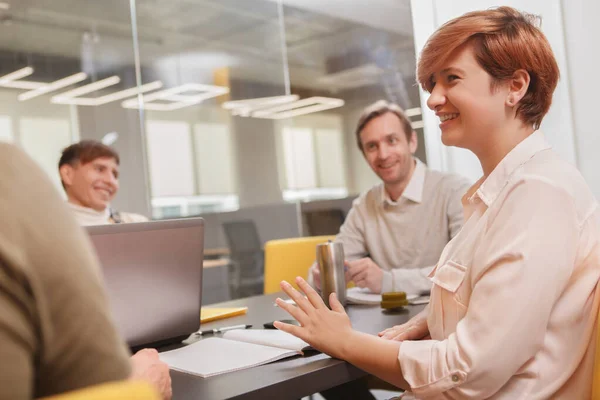 女企业家笑着 在办公室开会时与她的创意团队交谈 — 图库照片
