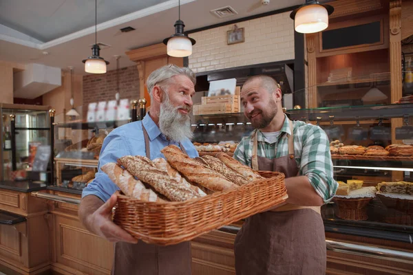 Two male bakers father and son selling delicious bread at their bakery store
