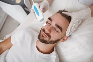 Sakallı bir adamın kozmetoloji salonundan yüz ultrasonu temizleme ameliyatı olurken en iyi görüntüsü.