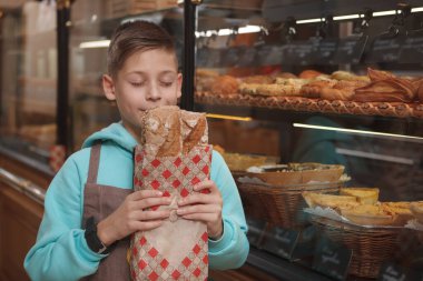 Önlük giyen, aile pastanesinde taze ekmek kokusu alan sevimli genç bir çocuk.
