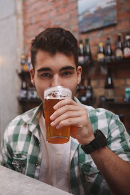 Bira barında bira içen yakışıklı bir adamın dikey görüntüsü.