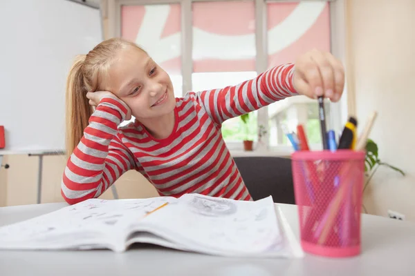 教室で絵を描きながら 美しいブロンドの髪の若い女の子が笑顔 色鉛筆を選ぶ 魅力的な女子高生はスケッチを楽しみ アートクラスの宿題をする — ストック写真