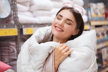 Mutlu ve güzel bir kadının sıcak bir battaniyeye sarınıp ev eşyaları alırken keyfini çıkarması.