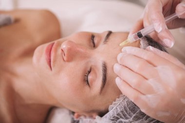 Çekici bir kadın güzellik kliniğinde kırışıklık önleyici iğneler yaptırıyor. Kozmetoloji, gençleştirme konsepti