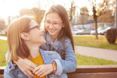 Annesini kucaklayan mutlu genç kız, sonbaharda parkta eğleniyor, boşluğu kopyalıyor.