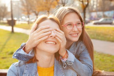 Mutlu genç kız gülüyor, elleriyle annesinin gözlerini kapatıyor. Sevimli küçük kız annesine sürpriz yapıyor.