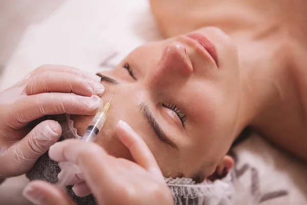 俯瞰一位妇女的近视 她的额头被注射了填充物 专业的美容师将透明质酸注入女性病人的皮肤 — 图库照片