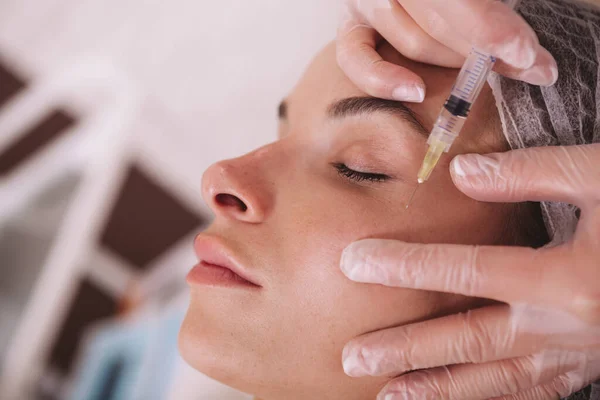 在美容院接受抗皱治疗的一位美女的近照 专业美容师将面部填充物注入女性客户的皮肤 — 图库照片