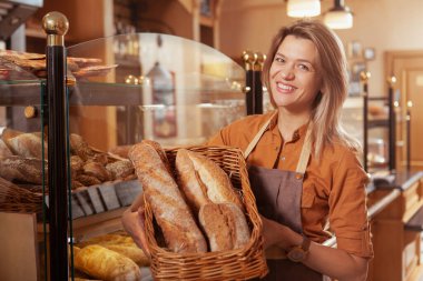 Fırınında selicious ekmeği satan gururlu bayan girişimci. Kadın fırıncı gülümsüyor, elinde mola sepeti var.