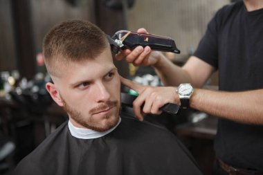 Berber dükkanında yeni saç kesimi yaptıran genç ve çekici bir adamın yakın çekimi.