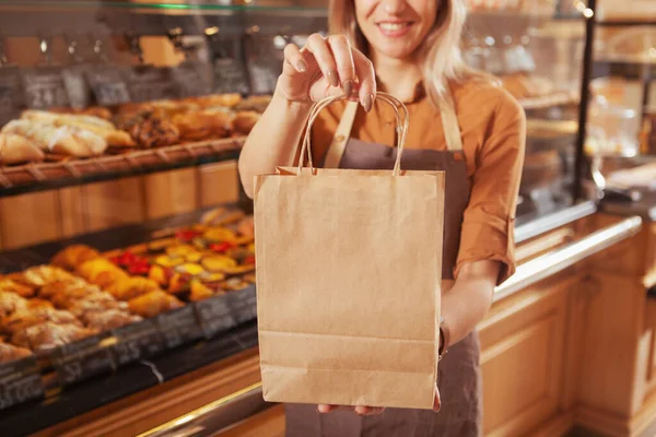 カフェの女性パン職人の手によるリサイクル可能なショッピングバッグの切り取られたショット 菓子販売 — ストック写真