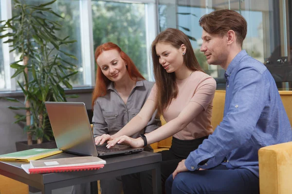 Group of business people working on a laptop together at modern office