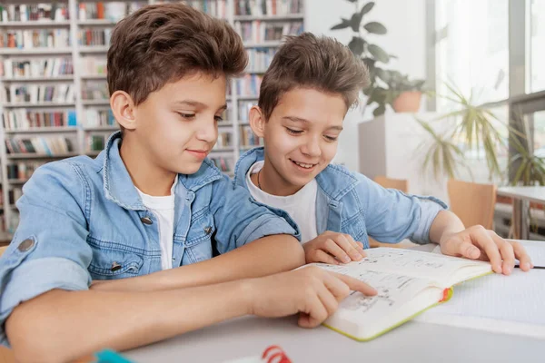 図書館で一緒に本を読んでいる二人のチャーミングな双子の男の子 友情の概念 — ストック写真