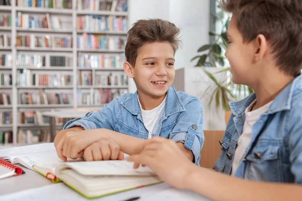 図書館で一緒に勉強している二人の若い幸せな男の子 双子の兄弟が本を読みながら話す — ストック写真