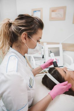 Çalışırken tıbbi maske takan profesyonel bir kozmetikçinin dikey fotoğrafı.