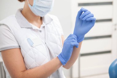 Female doctor putting on rubber gloves, working at the hospital