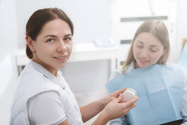 Joven Dentista Sonriendo Cámara Mientras Trabaja Con Una Paciente — Foto de Stock