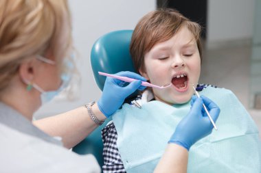 Profesyonel dişçi tarafından diş tedavisi gören genç bir çocuk.