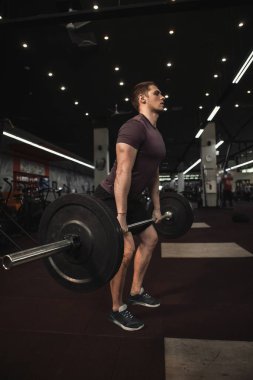 Spor salonunda halter kaldıran güçlü bir sporcunun dikey çekimi.