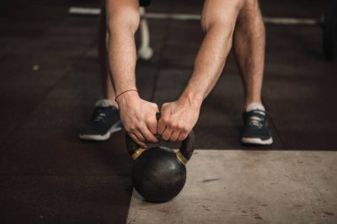 Tanınmayan erkek sporcu kettlebell ile çalışıyor.