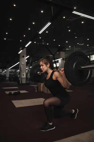 Vertical shot of a sportwoman doing lunges with barbell