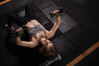 Spor salonundaki dambıllarla göğüs masajı yapan bir sporcunun en iyi görüntüsü.