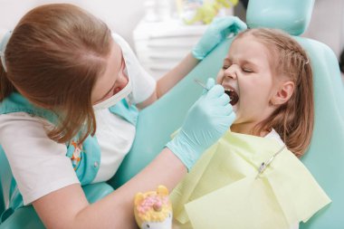 Little girl having dental checkup by professional dentist