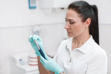 Female professional dentist holding her dental tools, working at her clinic, copy space