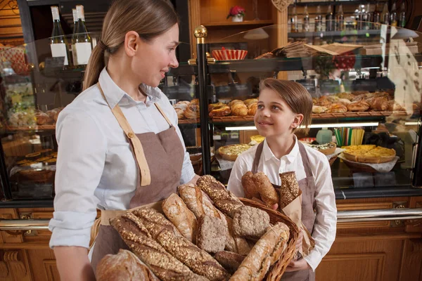 魅力的な若い男の子と彼の母親プロのパン屋彼らの家族のパン屋でおいしいパンを販売 — ストック写真